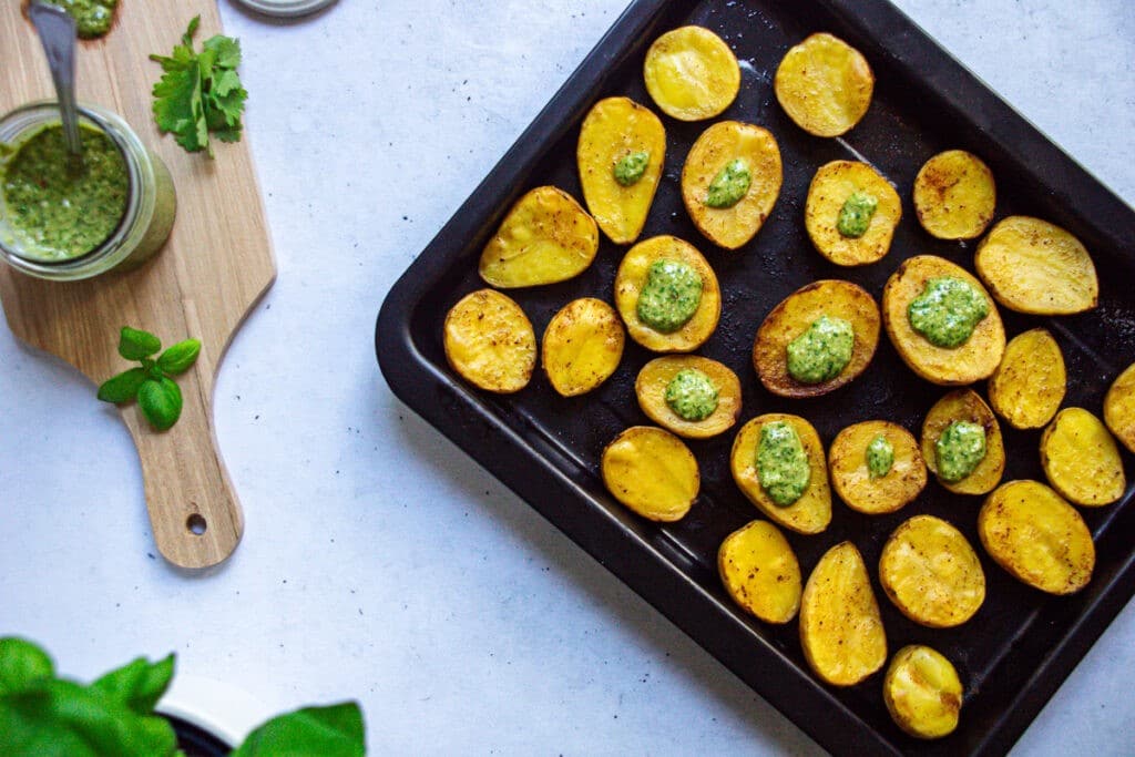 Ofenkartoffeln auf einem Backblech mit grünem Pesto